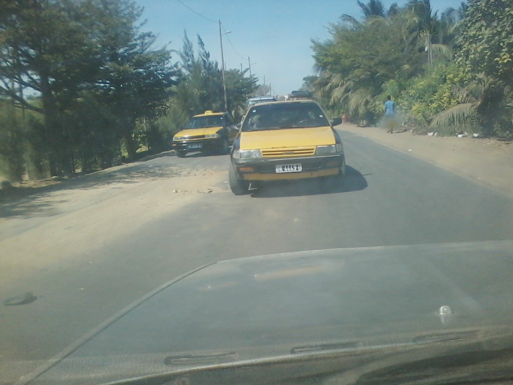Ce véhicule taxi est obligé de se déporter sur gauche pour éviter ce grand trou. C'est sur l'axe entre Croisement Cambérène et Rond-Point La Case